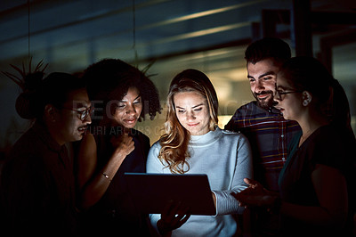 Buy stock photo Shot of a group of young businesspeople using a digital tablet during a late night at work
