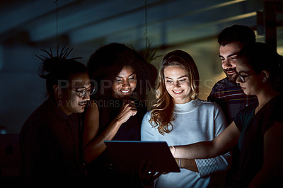 Buy stock photo Shot of a group of young businesspeople using a digital tablet during a late night at work