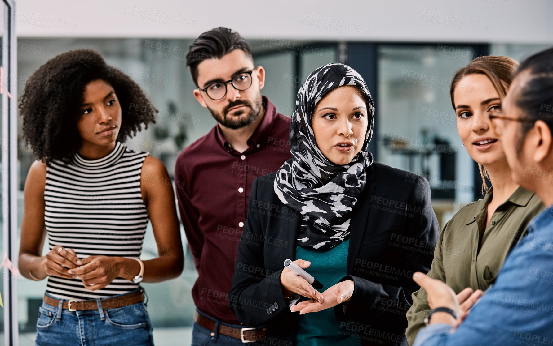 Buy stock photo Shot of a group of young businesspeople planning and writing notes on a glass wall in an office at work