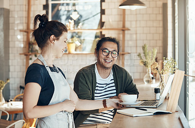 Buy stock photo Shot of a friendly young waitress serving coffee to a handsome young man in a coffee shop during the day