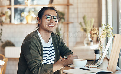 Buy stock photo Portrait of a handsome young man sitting and smiling while working on his laptop in a coffee shop