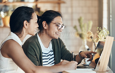 Buy stock photo Shot of young business partners sitting and working with each other in a coffee shop during the day