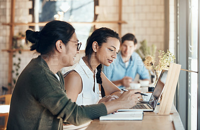 Buy stock photo Shot of young business partners sitting and working with each other in a coffee shop during the day