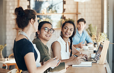 Buy stock photo Shot of a friendly young waitress serving coffee to young business partners in a coffee shop during the day