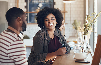 Buy stock photo Shot of young business partners sitting and talking with each other in a coffee shop during the day