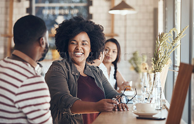 Buy stock photo Shot of young business partners sitting and talking with each other in a coffee shop during the day