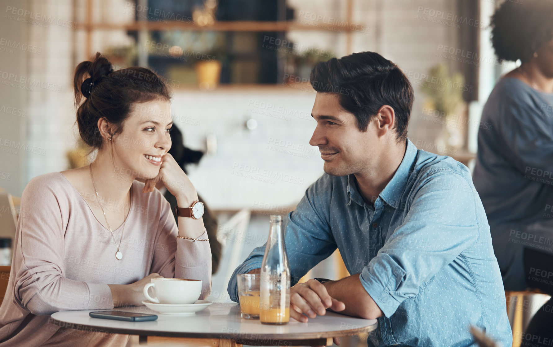Buy stock photo Shot of an affectionate young couple sitting with each other in a coffee shop during the day