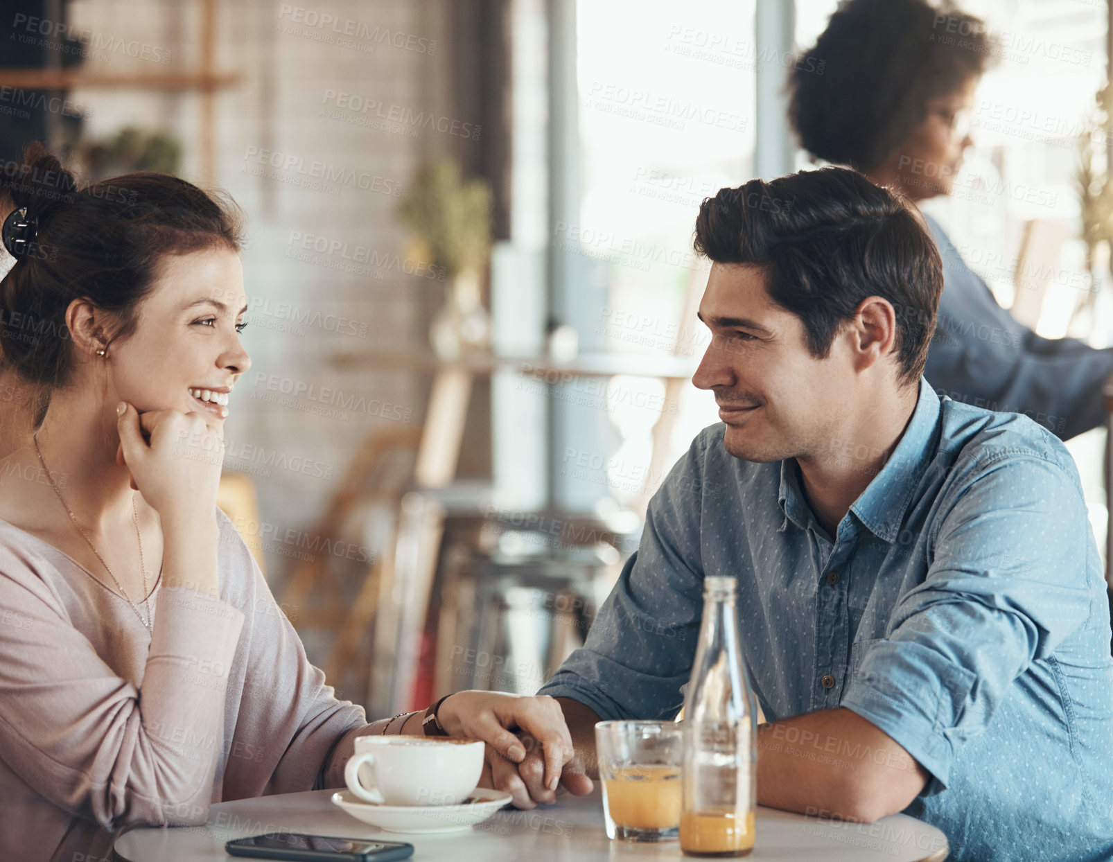 Buy stock photo Shot of an affectionate young couple sitting with each other in a coffee shop during the day