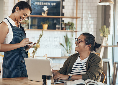 Buy stock photo Shot of a friendly young waitress writing down an order for a handsome young businessman in a coffee shop