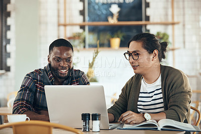 Buy stock photo Shot of handsome young businessmen sitting and working on a laptop in a coffee shop during the day