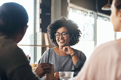 Buy stock photo Shot of an attractive young woman sitting and smiling with her friends in a coffee shop during the day