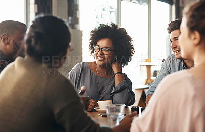 Buy stock photo Shot of a young diverse group sitting together and smiling in a coffee shop during the day