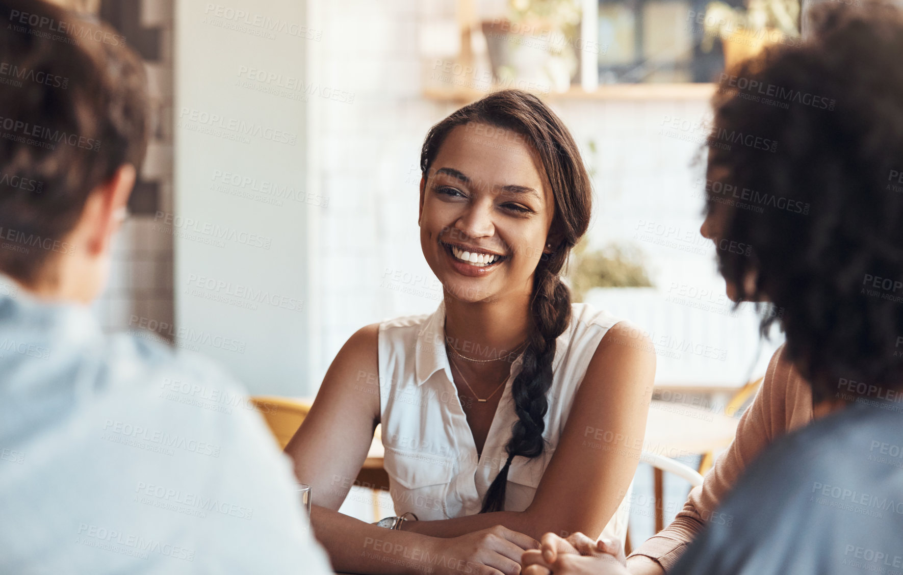 Buy stock photo Shot of an attractive young woman sitting and smiling with her friends in a coffee shop during the day
