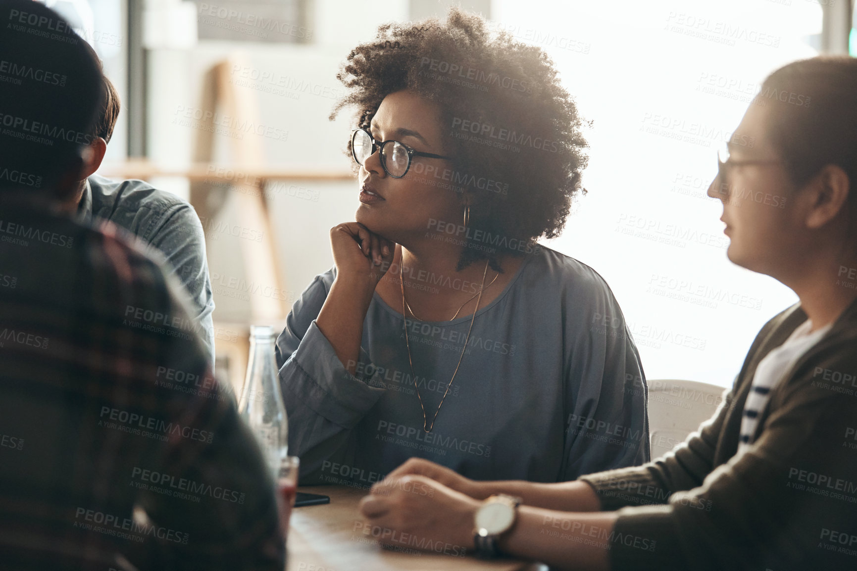 Buy stock photo Shot of a diverse young group of business people sitting and listening to each other in a coffee shop during the day