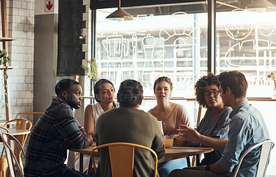 Buy stock photo Shot of a diverse young group of business people sitting and listening to each other in a coffee shop during the day