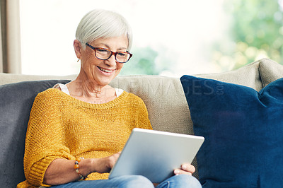 Buy stock photo Shot of a senior woman using a digital tablet on the sofa at home
