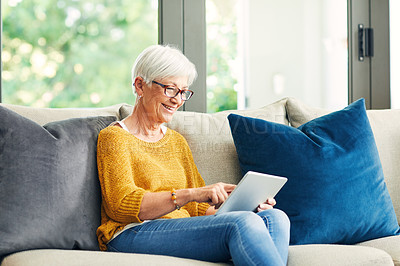 Buy stock photo Shot of a senior woman using a digital tablet on the sofa at home