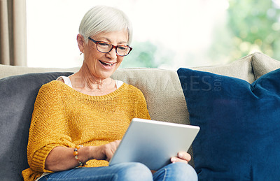 Buy stock photo Shot of a senior woman using a digital tablet on the sofa at home