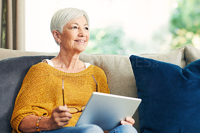 Buy stock photo Shot of a senior woman using a digital tablet on the sofa at home