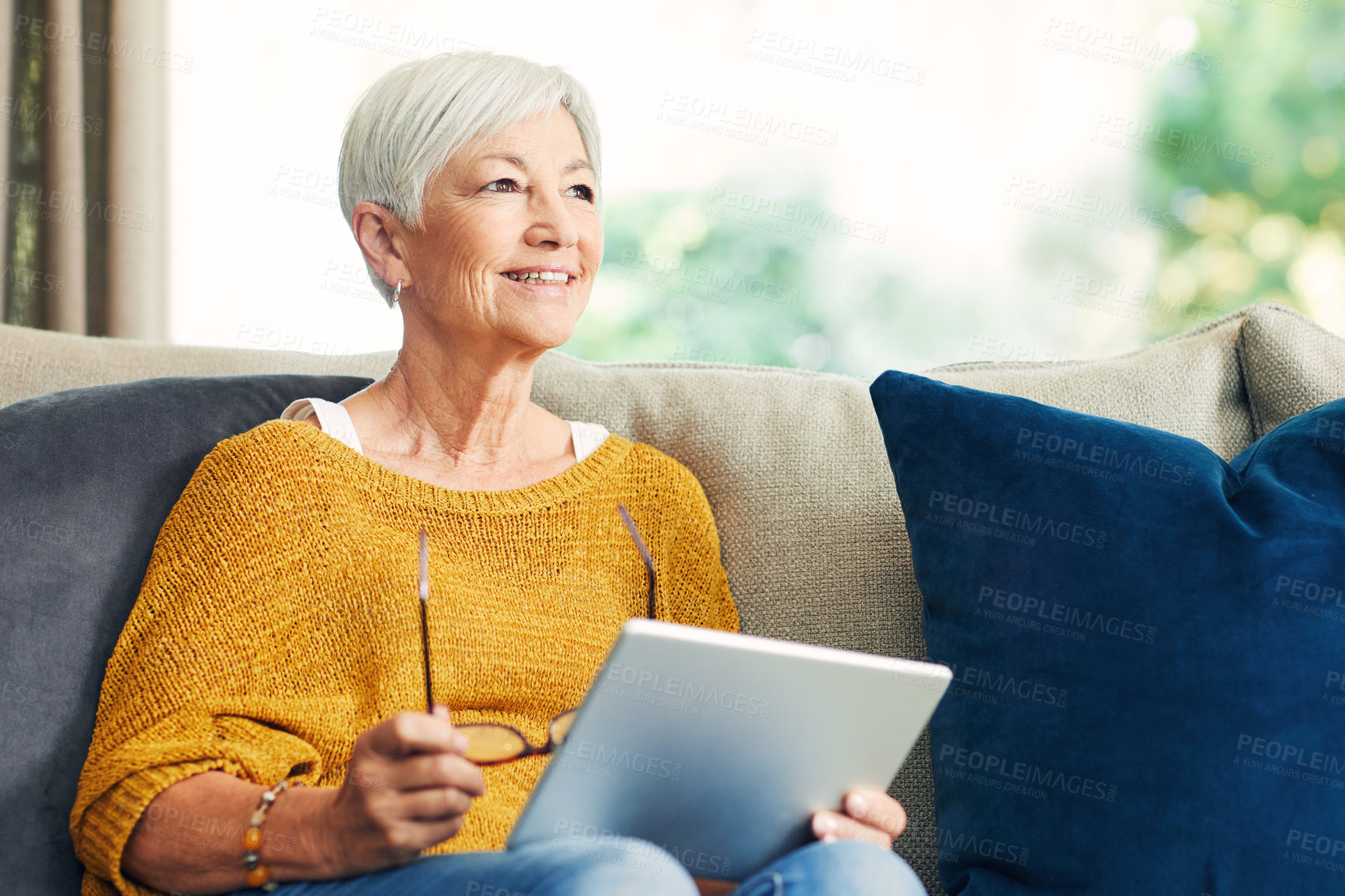 Buy stock photo Shot of a senior woman using a digital tablet on the sofa at home