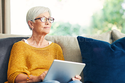 Buy stock photo Shot of a senior woman using a digital tablet on the sofa at home