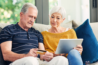 Buy stock photo Shot of a senior couple using a credit card and digital tablet on the sofa at home