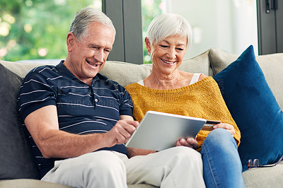 Buy stock photo Shot of a senior couple using a digital tablet on the sofa at home