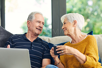 Buy stock photo Shot of a senior couple using a laptop on the sofa at home