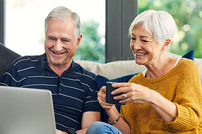 Buy stock photo Shot of a senior couple using a laptop on the sofa at home