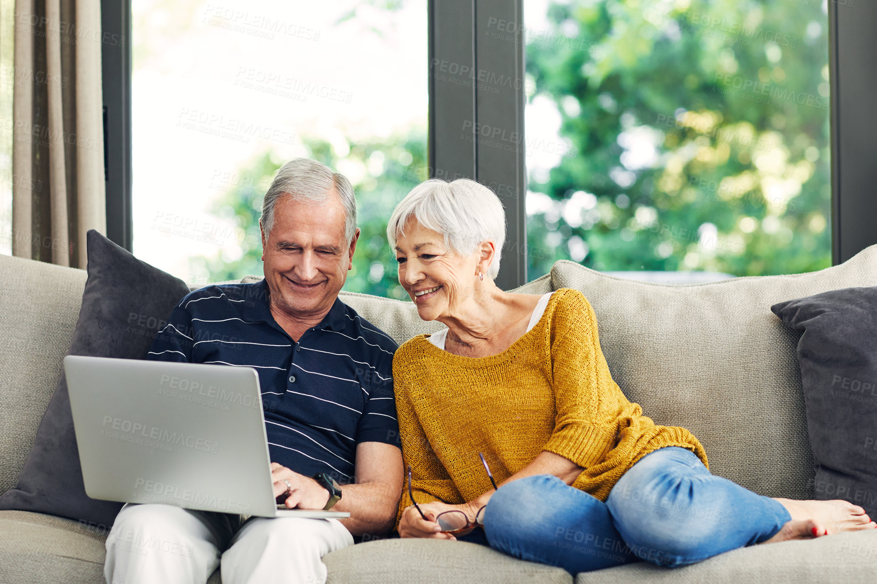 Buy stock photo Shot of a senior couple using a laptop on the sofa at home