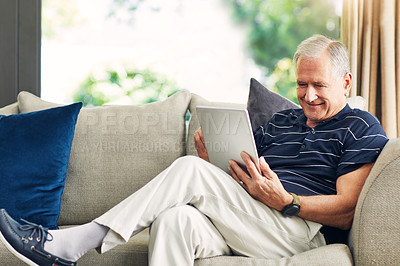 Buy stock photo Shot of a senior man using a digital tablet on the sofa at home