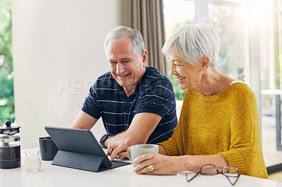 Buy stock photo Shot of a senior couple using a digital tablet and having coffee at home