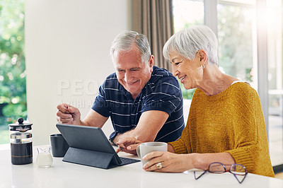 Buy stock photo Shot of a senior couple using a digital tablet and having coffee at home