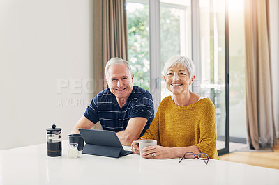 Buy stock photo Shot of a senior couple using a digital tablet and having coffee at home