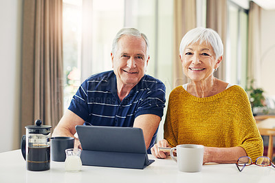 Buy stock photo Shot of a senior couple using a digital tablet and having coffee at home