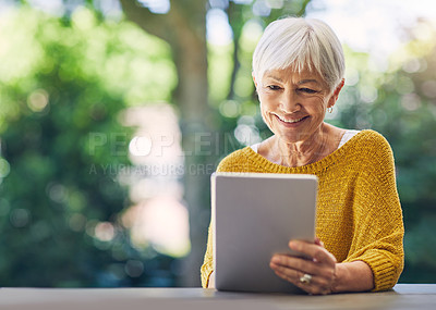 Buy stock photo Shot of a senior woman using a digital tablet in her backyard