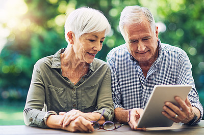 Buy stock photo Shot of a senior couple using a digital tablet together in their backyard