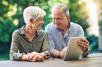 Buy stock photo Shot of a senior couple using a digital tablet together in their backyard
