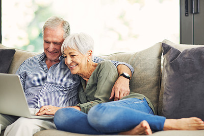 Buy stock photo Shot of a senior couple using a laptop on the sofa at home