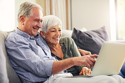 Buy stock photo Shot of a senior couple using a laptop on the sofa at home