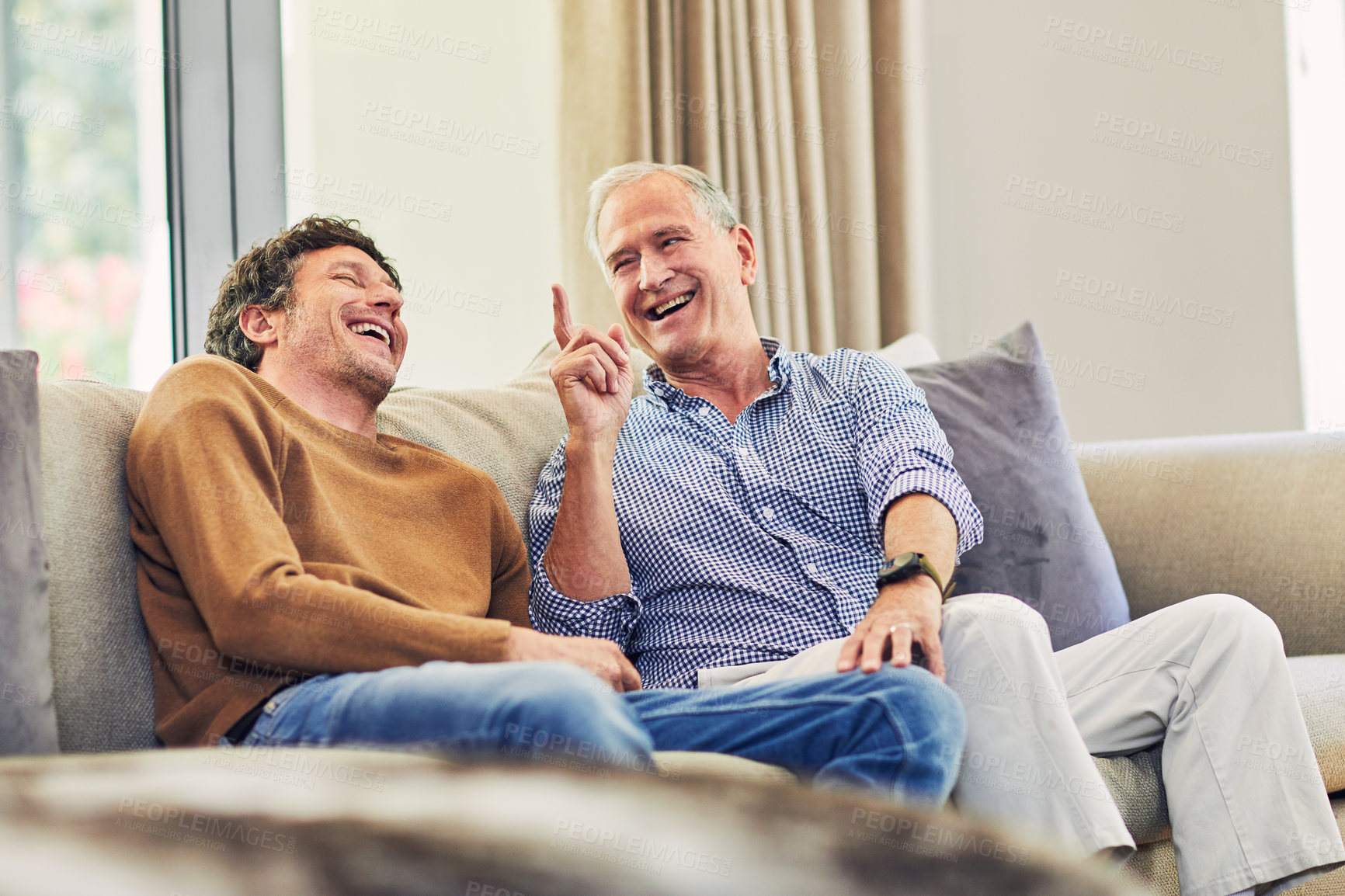 Buy stock photo Shot of a mature man and his elderly father sitting on the sofa at home and chatting