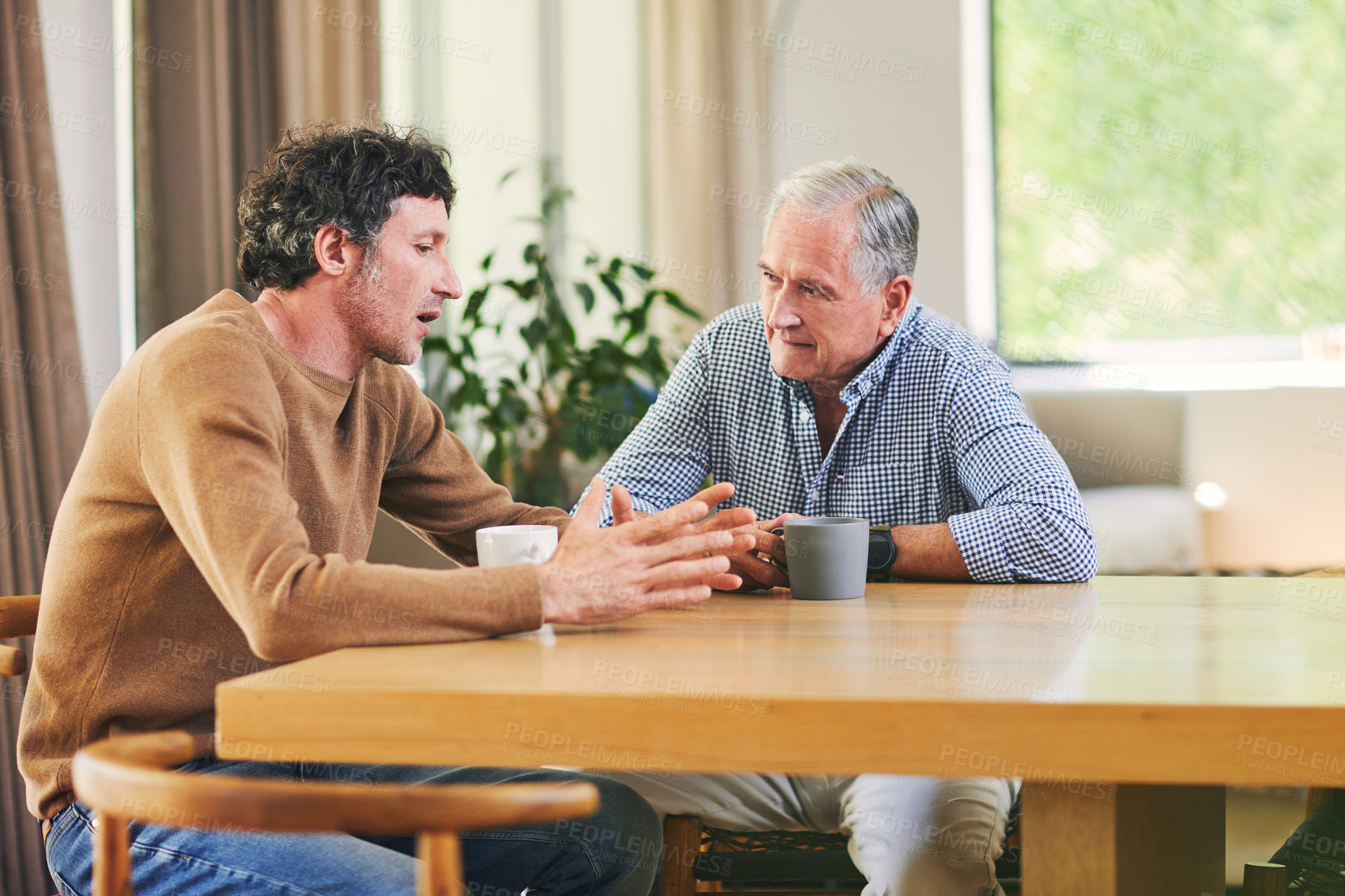 Buy stock photo Shot of a mature man and his elderly father having coffee and a chat at home