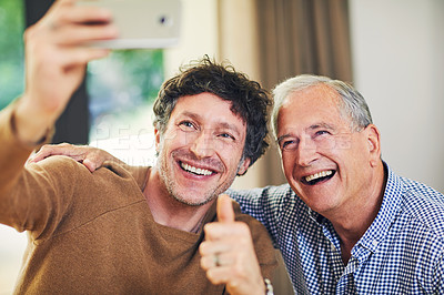 Buy stock photo Shot of a mature man and his elderly father taking selfies together at home