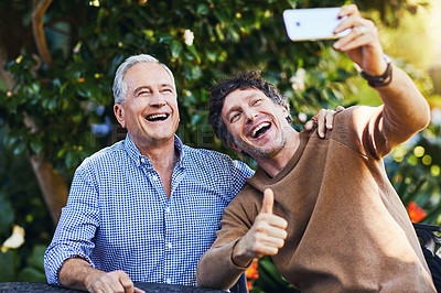 Buy stock photo Shot of a mature man and his elderly father taking selfies together in a garden