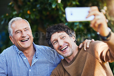 Buy stock photo Shot of a mature man and his elderly father taking selfies together in a garden