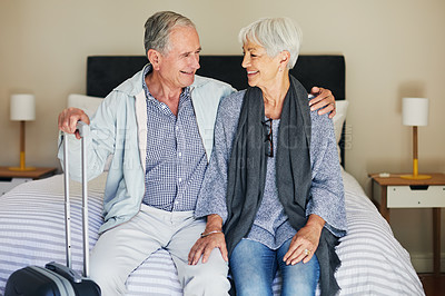 Buy stock photo Shot of a happy senior couple sitting on a bed in their hotel room
