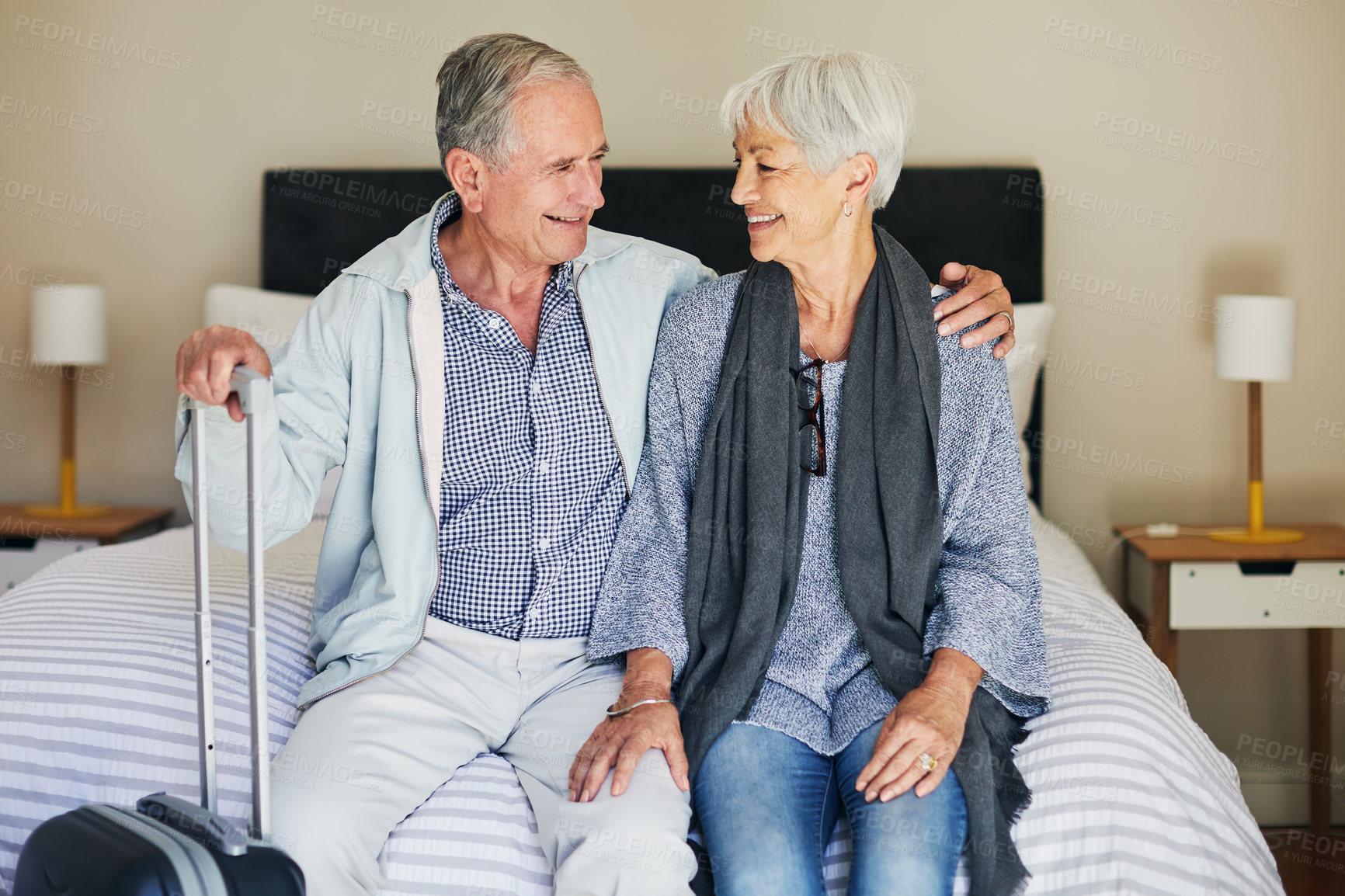 Buy stock photo Shot of a happy senior couple sitting on a bed in their hotel room