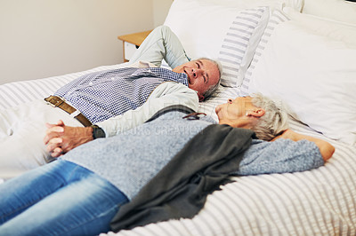 Buy stock photo Shot of a happy senior couple relaxing on a bed in their hotel room