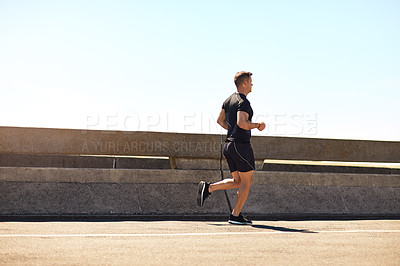 Buy stock photo Shot of a sporty young man out for a run on a bridge in the city
