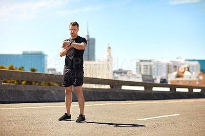 Buy stock photo Shot of a sporty young man looking at his wristwatch while out exercising
